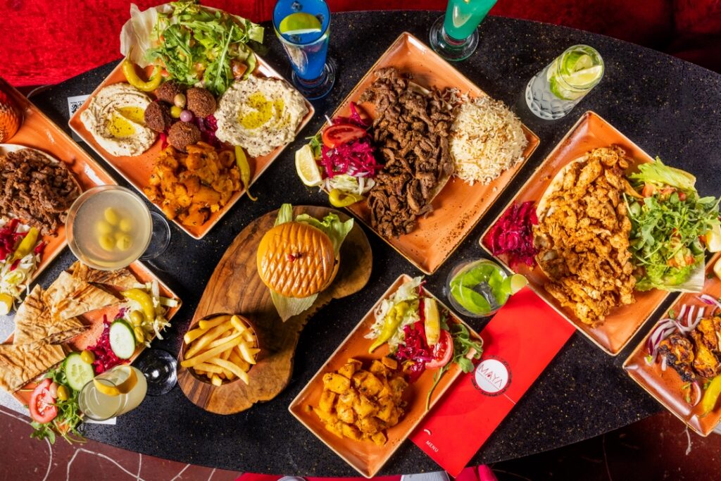 Overhead spread of mixed grills, fries, salads and drinks at Maya Lounge, a shisha lounge near Cockfosters