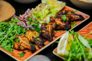 Grilled chicken wings on a wooden board with herbs and lemon at Maya Lounge