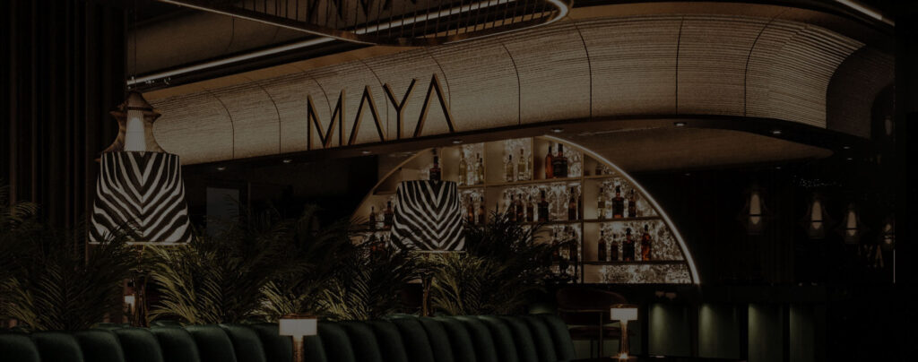 Lounge seating area with striped armchairs and bar under the MAYA sign, available for private hire